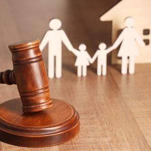 Gavel beside paper cutout family figures, symbolizing guardians