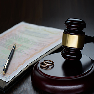 Judge's gavel, wedding rings, and legal document symbolizing divorce proceedings.